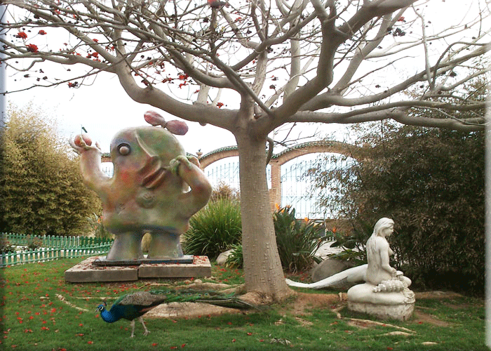 Pavo real junto a estatua en el Parque de Marinador